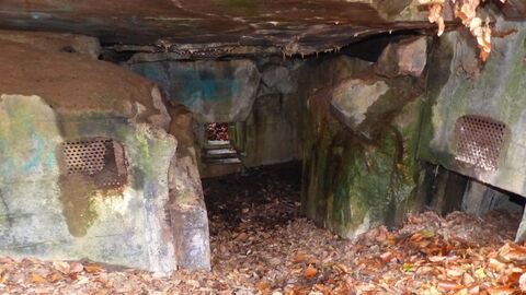 Blick in die Gasschleuse eines großen Manschaftsbunkers, die Schießscharte in der Bildmitte diente der davor befindlichen Eingangstür. Die Verschlüsse aus Stahl wurden bereits nach der Zerstörung des Bauwerks entfernt. Foto der Gasschleuse eines großen Manschaftsbunkers