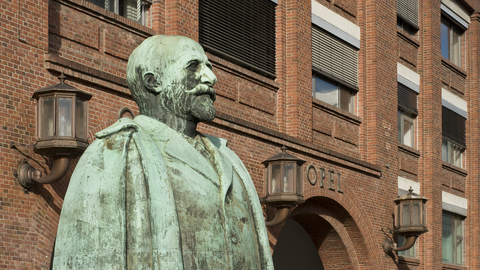 Foto. Das Adam-Opel-Denkmal vor dem Opel-Hauptportal in Rüsselsheim am Main.