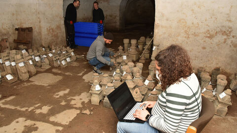 Man sieht Mitarbeitende des Transportunternehmens sowie Anna Steyer, Restauratorin im LfdH, die die Übergabe begleitet und dokumentiert im Tiefkeller des Biebricher Schlosses in Wiesbaden 
