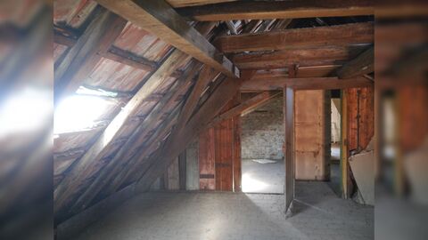 Blick in einen offenliegenden, hölzernen Dachstuhl. Der Fußboden ist teilweise gefliest.