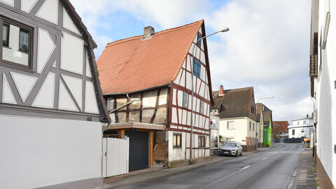 Ansicht Straßenseite Foto Straßenseite eines zweigeschossigen, giebelständigen Fachwerkhauses mit steilem Satteldach. Das Dach ist mit roten Biberschwanzziegeln gedeckt. Das Fachwerkgefüge ist sichtbar, seitlich teils Schäden an der Verputzung der Gefache.