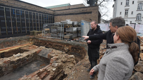 Foto. Dr. Sandra Sosnowski und Oberbürgermeister Frank-Tilo Becher betrachten die Grabung. Im Hintergrund Grabungsleiter Mateusz Nawrocki.