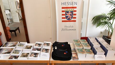 Infostand Tisch, auf dem verschiedene Broschüren und Taschen, kostenlos zum Mitnehmen liegen