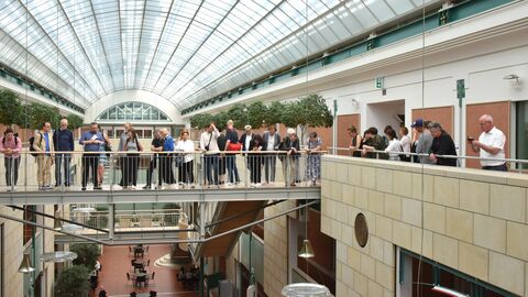 Gruppe guckt von einem offen gestaltenen oberen Geschoss in ein unteres Geschoss