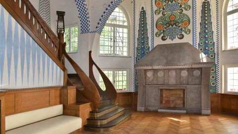 Der Innenraum nach der Sanierung Bild von dem Innenraum mit ausladender Holztreppe und buntem Mosaik