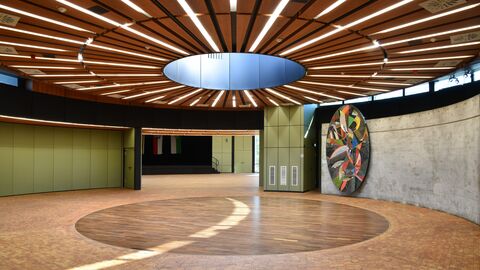 Rotunde in der Stadthalle Raum mit Holzboden und Holzdecke, sowie grünen Wandelementen