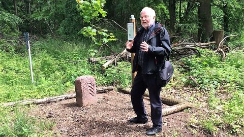 Dr. Wilhelm Ott Dr. Ott steht vor einem historischen Grenzstein und erzählt etwas über diesen Grenzstein