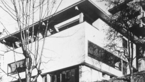 Schwarz-Weiß-Bild eines dreistöckigen Gebäudes mit Fensterbändern und einer langen Loggia.