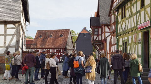 Nach dem Mittagessen wurde das Tagungsthema auf einem Rundgang durch den Hessenpark vertieft Gruppe steht versammelt vor einem Fachwerkhaus