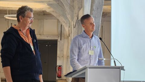 Der Besitzer und der Generalunternehmer berichten über die Arbeiten an einem Fachwerkhaus in Hochheim. Zwei Männer stehen nebeneinander an dem Redepult.