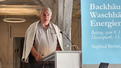 Siegfreid Becker hielt einen Vortrag über gemeinsam genutzte Einrichtungen (wie Backhäuser), die in der Vergangenheit zum Energie sparen genutzt wurden Mann steht am Redepult und spricht