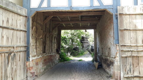 Durchfahrt von der Dorfstraße auf den Hinterhof Blick durch das geöffnete hölzerne Durchfahrtstor von der Dorfstraße aus.