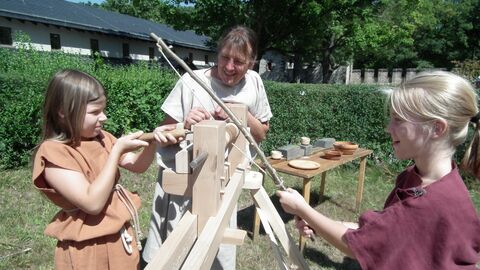 Ein Programm für Groß und Klein! Kinder drechseln nach römischer Art unter Aufsicht.