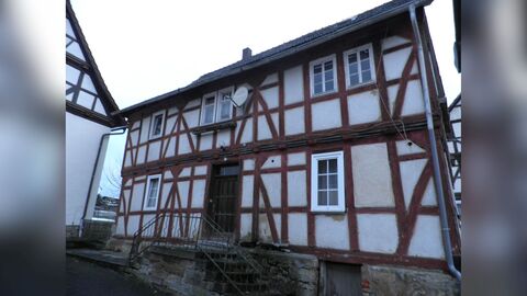 Zweigeschossiger Fachwerkbau mit mittig liegender doppelläufiger Treppe und Eingangstür. 