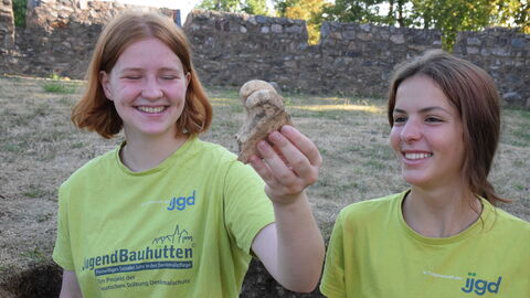 Bei den Arbeiten im Gelände entdecken die Freiwilligen immer wieder spannende Funde. Zwei Freiwillige mit Fund.