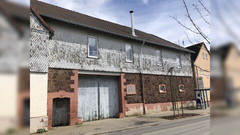 Zweigeschossiges traufständiges Gebäude mit einem Großen Einfahrtstor. Das Erdgeschoss mit sichtbarem Tuffmauerwerk, darüber mit Zungenschindeln verkleidet.
