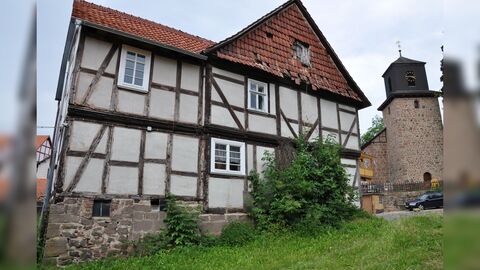 Giebelseite des Wohnhauses Blick auf die Giebelseite eines Fachwerkwohnhauses. Das Giebeldreieck ist mit Dachziegeln verkleidet. Im Hintergrund eine Kirche.