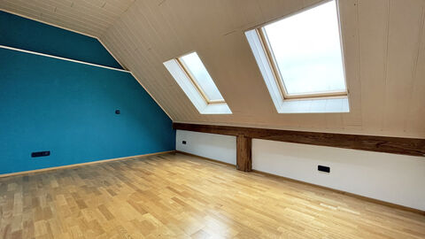 Heller Raum mit Dachfenstern und Parkettboden. 