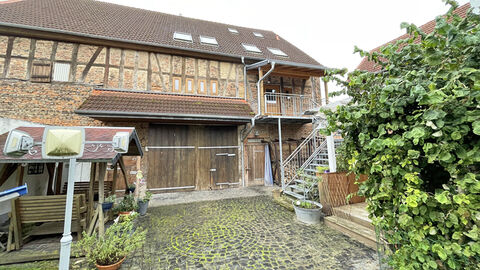 Hofansicht einer Scheune mit ausgemauertem Fachwerk und seitlichem Treppenaufgang.