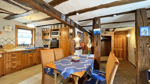 Blick auf einen Essbereich in einem Fachwerkwohnhaus mit offener Holzbalkendecke. 