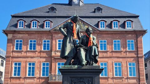 Statur der Gebrüder Grimm im Hanau ist mit orangenen Schals geschmückt.