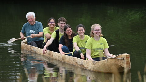 Neben der Arbeit am Brunnen durfte auch eine Fahrt in dem von einem Team der Zeiteninsel handgefertigten Nachbau eines historischen Einbaums nicht fehlen. Freiwillige in einem Einbaum.