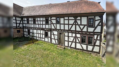 Fachwerkhaus mit weißen Gefachen und braun gestrichenem Fachwerk, sowie einer roten Dacheindeckung