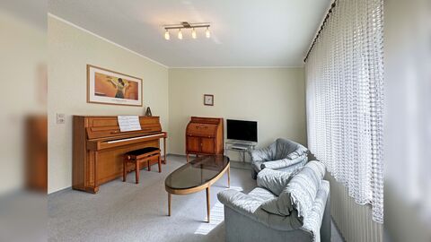 Zimmer mit Klavier und grauen Sofas