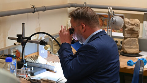 Staatsminister Timon Gremmels betrachtet eine römische Buntmetallmünze