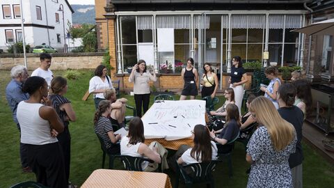 Die Teilnehmenden sitzen um einen Tisch und besprechen die Arbeiten
