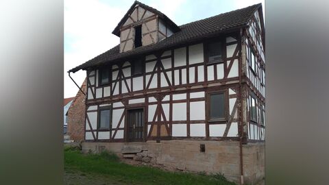 Das Haus wird von der Hofseite erschlossen Traufseitige Ansicht eines zweigeschossigen Fachwerkhauses auf Sandsteinsockel mit Zwechhaus im Dachbereich