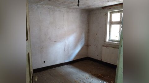 Innenraum Blick in einen Raum mit weißen Wänden und Boden aus Holzdielen.