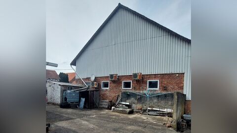 Giebelseite eines mehrstöckigen Gebäudes mit sichtbarem Mauerwerk im Erdgeschoss und Metallverkleidung in den oberen Geschossen