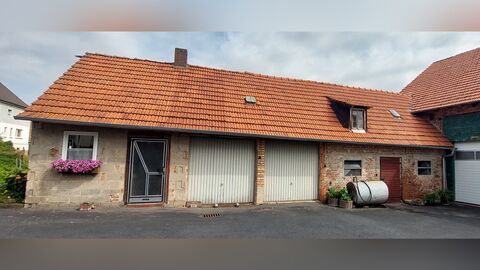 Einstöckiger Bau mit sichtbarem Mauerwerk und hohem, rot eingedecktem Dach