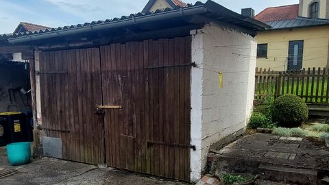 Schuppen aus weißem Mauerwerk mit Holztür