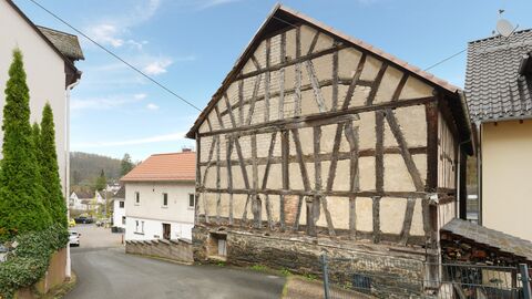 Die Scheune mit teilweise freigelegtem Fachwerk  Gebäude auf Natursteinsockel hier mit Blick auf die Giebelseite. Die Fachwerkkonstruktion ist freigelegt, die Gefache größtenteils mit Lehmziegeln ausgefüllt.