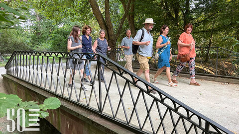 Gäste der Weinprobe laufen über eine der vielen Brücken im Park.