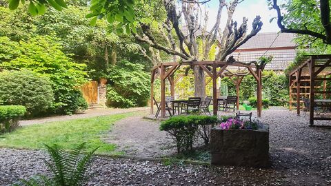 Sitzgruppen rund um einen Baum, insbesondere im linken Bildteil gibt es viel Begrünung