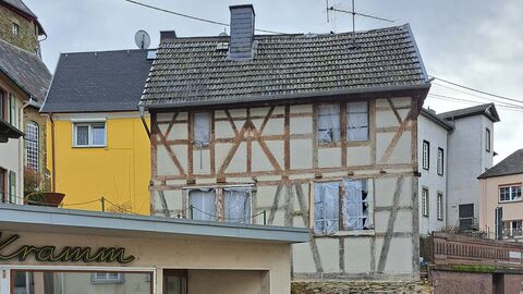 Fachwerkfassade mit zugeklebten Fenstern und schwarzer Dacheindeckung