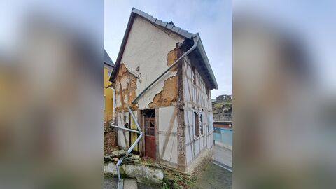 Fachwerkhaus mit zugeklebten Fensteröffnungen. Schwarze Dacheindeckung und verschieferter Giebel.