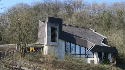 Talseitige Aufnahme der Trauerhalle, einem Gebäude aus Sichtbeton mit Eternitschieferdächern. 