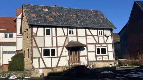 Die Eingangsfassade des Gebäudes Ortsstraße 20 in Neukirchen-Christerode Fachwerkhaus auf Natursteinsockel mit zwei Vollgeschossen und mittig gelegenem Eingang