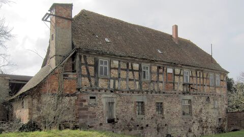 Blick von Norden auf das Gebäude Längsseite eines zweigeschossigen Baus mit einem massiv gemauerten Erdgeschoss und einem Fachwerkobergeschoss mit beidseitigem Halbwalm.
