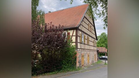 Ostfassade des Gebäudes Großvolumiges Fachwerkhaus mit Erdgeschoss aus Bruchstein und einem Satteldach mit roter Biberschwanzeindeckung.