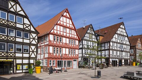 Das ehemalige Kaufmannshaus (zweites Haus v. L.) liegt direkt am Marktplatz von Hofgeismar Mehrere nebeneinander angeordnete, giebelständige Häuser. Das ausgezeichnete Objekt hat ein hellrot angestrichenes Renaissance-Fachwerk