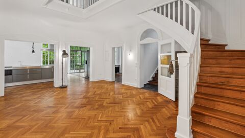 Empfangsbereich Weiß gestrichener Raum mit Holztreppe und Fischgrätparkett