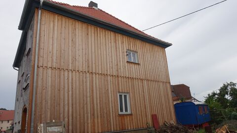Nachträglich mit Holz verkleidete Nordseite Zwei mit Holz verkleidete Vollgeschosse. Pro Etage gibt es ein kleines Fenster.