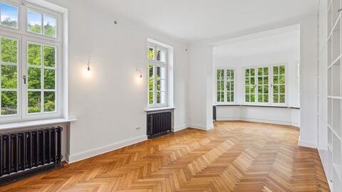 Bibliothek Weiß gestrichener, langer Raum mit Erker, Fischgrätenparkett und mehreren Sprossenfenstern