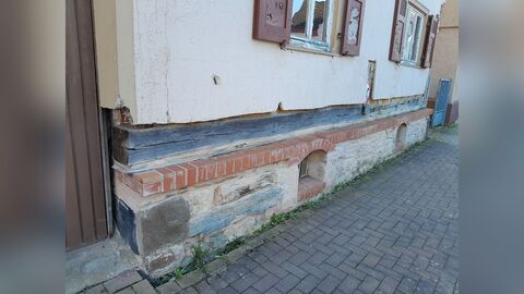 Sockel aus Naturstein, auf dem ein Holzbalken aufliegt
